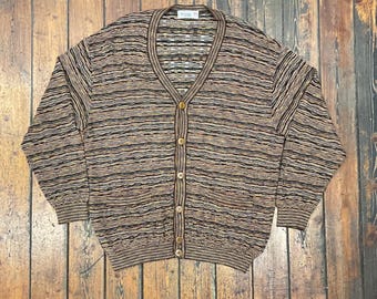 May include: A vintage button-down cardigan sweater with a V-neckline. The sweater features horizontal stripes in shades of brown, black, and tan. It has long sleeves and a classic fit. The sweater is made of a knit material and has a label at the neckline.
