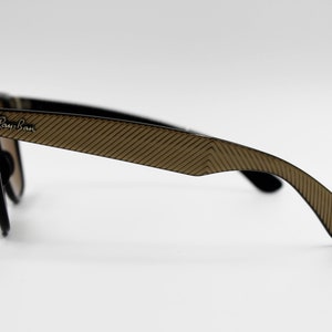 May include: Black Ray-Ban sunglasses with brown patterned arms. The sunglasses have a classic aviator style.