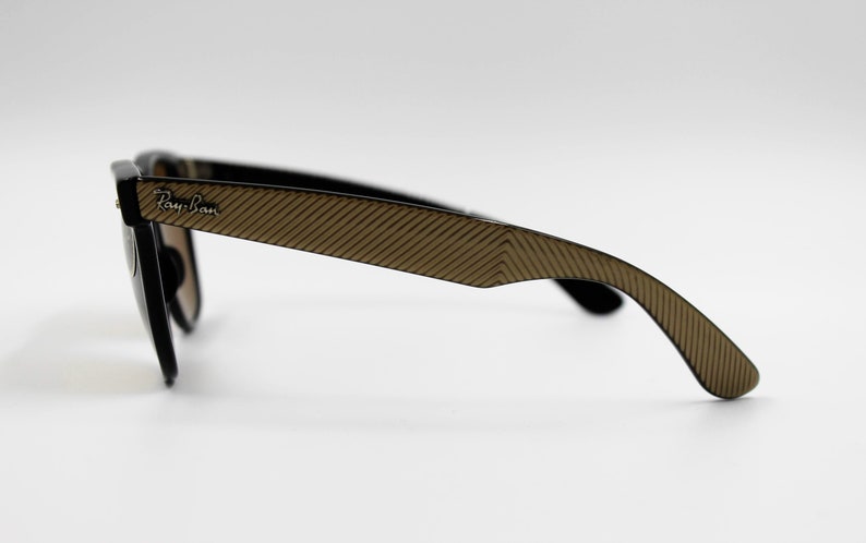 May include: Black Ray-Ban sunglasses with brown patterned arms. The sunglasses have a classic aviator style.