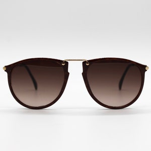 Puede incluir: Gafas de sol aviador marrones con puente dorado y lentes marrones.
