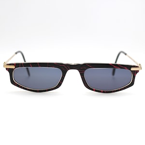 Op de afbeelding: Een paar zwarte zonnebrillen met rode marmeren monturen en donkergrijze glazen.