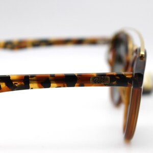 May include: Tortoise shell sunglasses with gold accents and the Ray-Ban logo on the side.