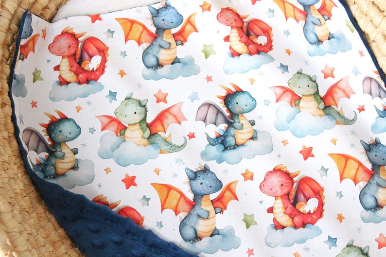 May include: A white fabric with a repeating pattern of blue, green, and red dragons on clouds with orange and white stars. The fabric has a blue border.
