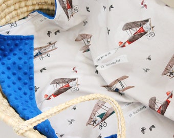 May include: A blue and white baby blanket with a pattern of airplanes and birds. The blanket has a soft, plush texture and is perfect for cuddling. The text "I love you as airplanes fly" is printed on the blanket.