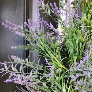 May include: A close-up of a lavender wreath with purple flowers and green leaves.