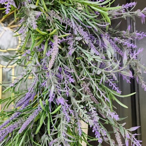 May include: A close-up of a lavender wreath with purple flowers and green leaves.