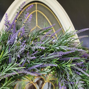 May include: A purple and green lavender wreath with a decorative window behind it.