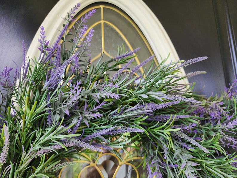 May include: A purple and green lavender wreath with a decorative window behind it.