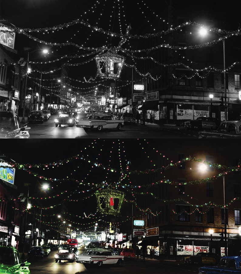 May include: A black and white photo of a city street at night, decorated with Christmas lights. The photo is split in half, with the top half showing the street in black and white, and the bottom half showing the street in color. The street is lined with buildings, and there are cars parked on both sides of the street. The street is decorated with Christmas lights, which are strung across the street and from the buildings. The lights are twinkling, and they create a festive atmosphere.
