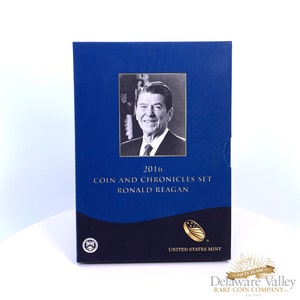 May include: A rectangular blue presentation box for the 2016 Ronald Reagan Coin and Chronicles Set. The front features a black and white portrait of Ronald Reagan, gold text, and the United States Mint logo in the bottom corner.