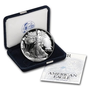 May include: A silver American Eagle one ounce coin in a blue velvet box with a white card that reads "American Eagle One Ounce".