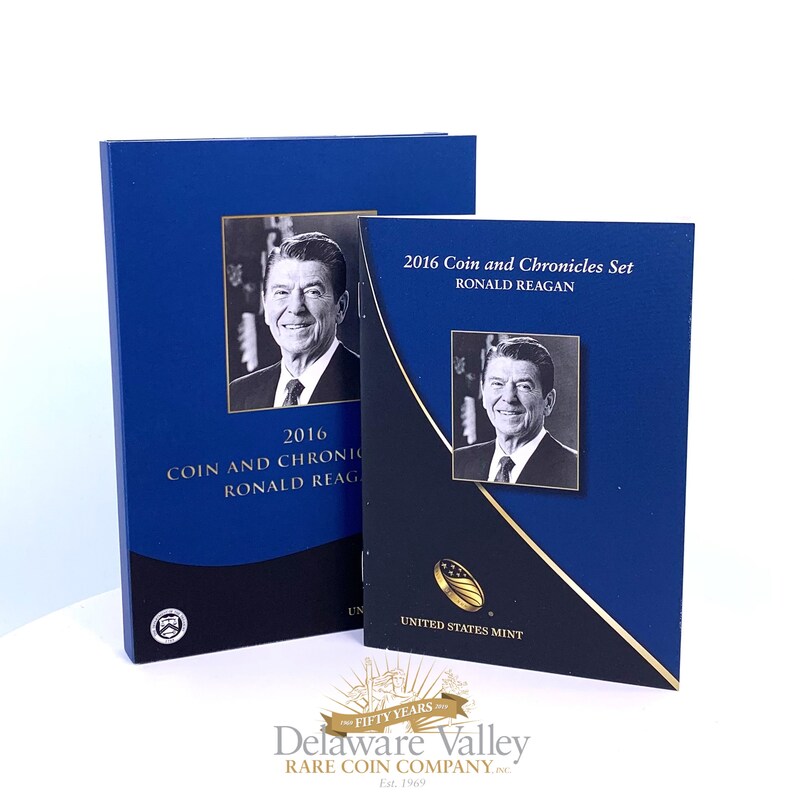 May include: A 2016 Coin and Chronicles Set featuring Ronald Reagan, consisting of a blue and black presentation folder and a matching slipcase. Both items display a black and white portrait of Ronald Reagan and the text 2016 Coin and Chronicles Set Ronald Reagan, with the United States Mint logo.