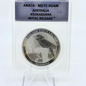 May include: A silver Australian Kookaburra coin in a protective case. The coin features a detailed image of a kookaburra bird perched on a fence. The case has text that reads "2016-P", "ANACS - MS70 DCAM", "AUSTRALIA KOOKABURRA INITIAL RELEASE" and "2016 1oz 999 SILVER".