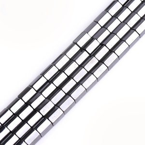 May include: A strand of black and silver square-shaped beads. The beads are arranged in a repeating pattern of black and silver.