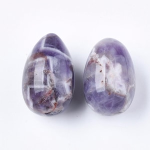 May include: Two amethyst crystal eggs, one with a purple and white pattern and the other with a purple and brown pattern.