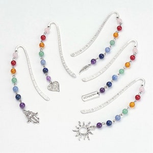 May include: Set of seven silver bookmark charms with colorful beaded chains. Each charm features a different design, including a heart, a sun, a hand, a feather, and a tag that says "Warrior".