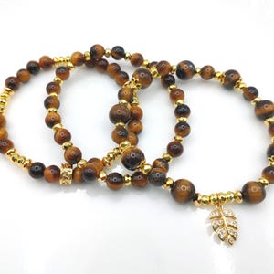 May include: A white ceramic mug with a black handle and the text "But First, Coffee" in a bold, black font. The mug is set against a blurred background, suggesting a cozy setting.