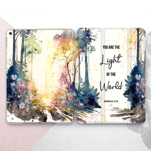 Peut inclure: Une peinture à l'aquarelle d'un sentier forestier avec un soleil qui brille à travers les arbres. Le texte "You are the light of the world. Matthew 5:14" est imprimé sur le côté droit de l'image.
