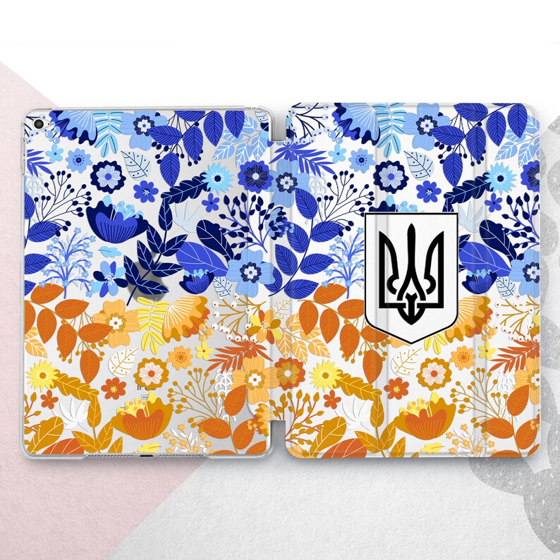 Peut inclure: &Eacute;tui pour tablette &agrave; motifs floraux bleus, oranges et blancs. L'&eacute;tui pr&eacute;sente un motif r&eacute;p&eacute;t&eacute; de fleurs et de feuilles. Un &eacute;cusson blanc avec un embl&egrave;me de trident noir est sur le c&ocirc;t&eacute; droit.