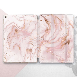 Könnte beinhalten: Eine iPad-Hülle mit einem pinkfarbenen und goldenen Marmormuster und einer durchsichtigen Rückseite. Die Hülle hat eine umklappbare Vorderseite.