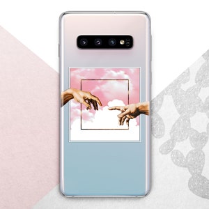 Könnte beinhalten: Eine Smartphone-Hülle mit einer quadratischen Grafik in der Mitte, die zwei Hände zeigt, die vor einem rosafarbenen Himmel mit weißen Wolken aufeinander zu greifen. Die Hülle hat einen Farbverlauf von hellrosa oben zu hellblau unten.