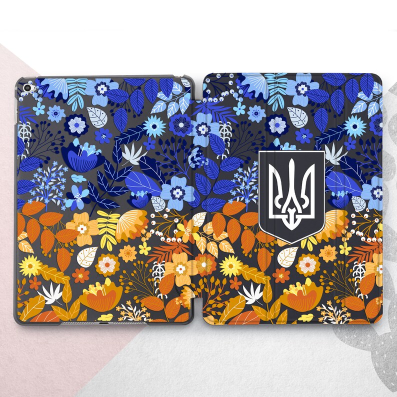 Peut inclure: Une coque de tablette avec un motif floral bleu, orange et jaune sur fond gris fonc&eacute;. L'&eacute;tui est divis&eacute; en deux parties et comporte un embl&egrave;me blanc et noir.