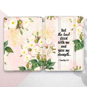 May include: A pink and white floral iPad case with a quote from the Bible: "But the Lord stood with me and gave me strength... 2 Timothy 4:17"