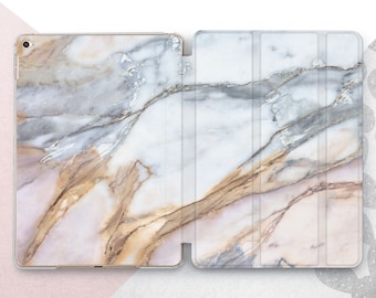 May include: A white and gold marble patterned iPad case with a fold-over front cover.