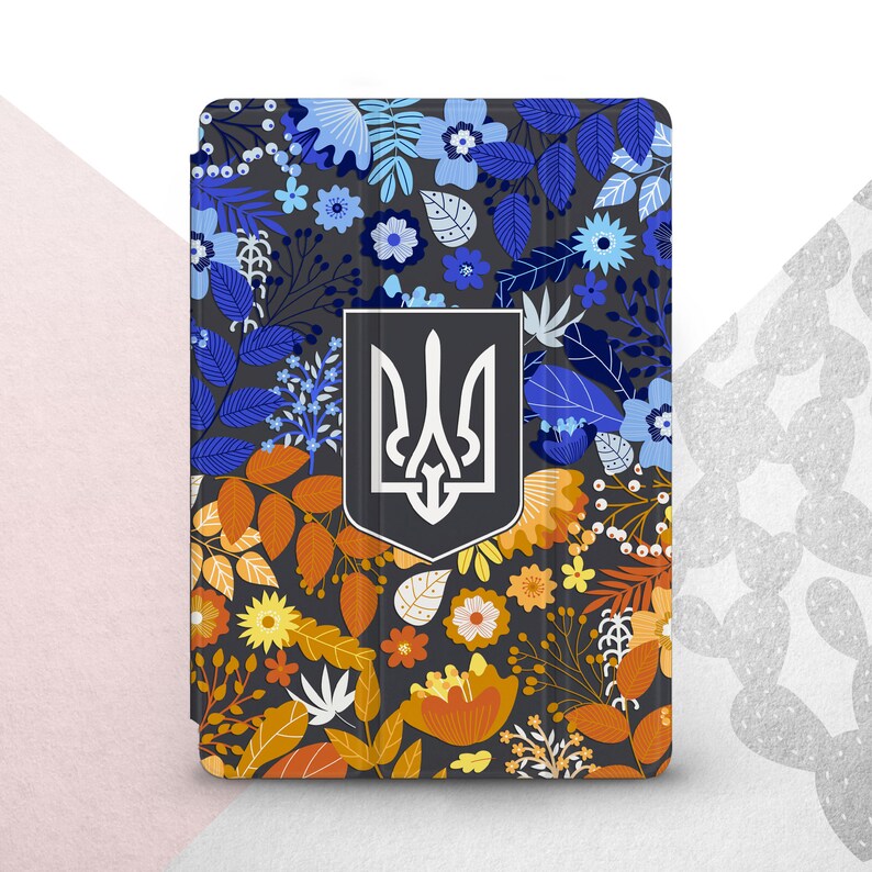 Peut inclure: &Eacute;tui pour tablette avec un motif floral bleu, orange et jaune sur fond gris fonc&eacute;. Il pr&eacute;sente un embl&egrave;me argent&eacute; et noir. Le design comprend diverses fleurs et feuilles.