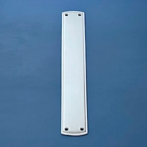 Puede incluir: Placa de puerta rectangular blanca con bordes redondeados y dos pequeños agujeros.