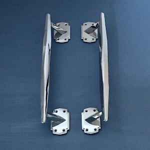 Peut inclure: Une paire de poignées de porte en chrome poli avec un design géométrique. Les poignées ont une forme carrée aux coins arrondis et une forme rectangulaire longue et étroite.