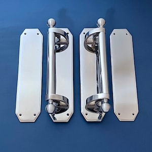 Pode incluir: Dois conjuntos de maçanetas de porta cromadas polidas com um design decorativo. Cada maçaneta tem uma placa traseira retangular e uma maçaneta redonda. As maçanetas estão montadas em um fundo azul.