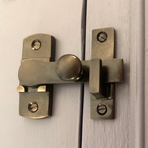 May include: A brushed nickel door latch with a rounded knob and a rectangular strike plate. The latch is mounted on a wooden door.