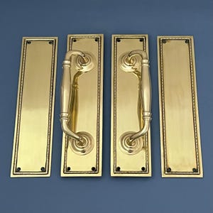 May include: Four polished brass door handles with a decorative beaded border. Each handle has a long, curved lever and a round rosette.