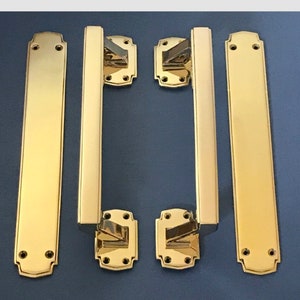 Puede incluir: Juego de manijas de puerta de latón pulido y placas rectangulares a juego. Las manijas son rectangulares con base cuadrada y manija curva. Las placas son largas y rectangulares con extremos redondeados y orificios.