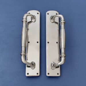 Peut inclure: Deux poignées de porte en nickel poli avec un design à levier. Les poignées ont une plaque arrière rectangulaire et un levier incurvé.