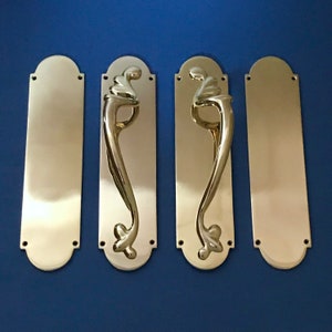 Pode incluir: Três placas de porta de latão com um design decorativo. As placas são retangulares com cantos arredondados e têm um acabamento polido.