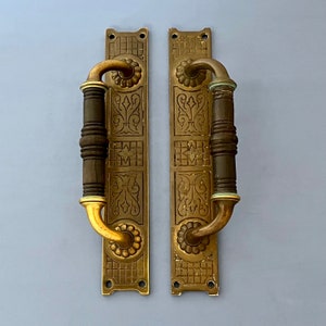 Könnte beinhalten: Zwei antike Messing-Türgriffe mit verzierten Designs und einer dekorativen Oberfläche. Die Griffe haben einen traditionellen Stil und sind aus massivem Messing gefertigt.