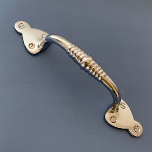 May include: A polished nickel door pull with a ribbed handle and a decorative, heart-shaped backplate.