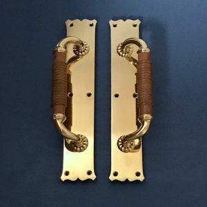 May include: A pair of polished brass door handles with decorative scrollwork and brown leather grips.