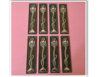 May include: Eight antique bronze door plates with a copper floral design. The plates are rectangular and have a slightly aged patina.