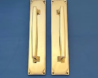 Könnte beinhalten: Zwei goldene Türgriffe mit rechteckiger Form und einem gebogenen Griff. Die Griffe sind poliert und haben eine glänzende Oberfläche.