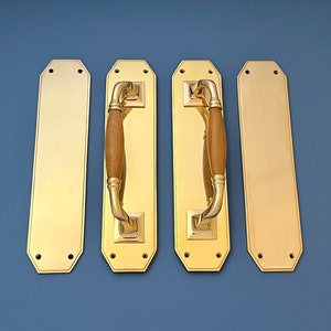 Puede incluir: Cuatro tiradores de puerta de latón pulido con inserto de madera. Dos de los tiradores tienen forma rectangular y dos tienen un diseño más ornamentado con la parte superior e inferior redondeadas.