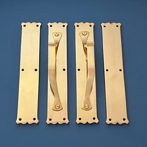 Puede incluir: Cuatro tiradores de puerta de latón con un diseño decorativo. Cada tirador tiene un diseño curvo y adornado y un pomo redondo simple.