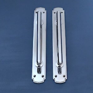 May include: Two polished chrome door pulls with a rectangular plate and a rounded handle. The pulls have a decorative design around the edges.