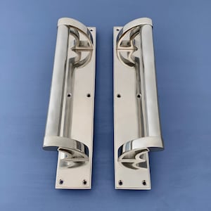 May include: Two polished chrome door handles with a curved design. The handles are mounted on rectangular plates with four screws each.