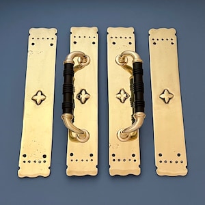 Puede incluir: Cuatro tiradores de puerta de latón adornados con detalles negros. Cada tirador presenta un diseño decorativo y un pomo negro.