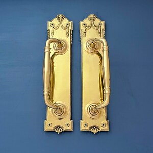 Puede incluir: Dos tiradores de puerta de latón ornamentados con un diseño decorativo y un estilo tradicional.