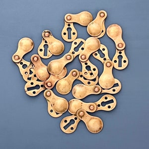 Op de afbeelding: Een verzameling messing sleutelgaten in verschillende vormen en maten. De sleutelgaten zijn willekeurig gerangschikt op een blauwe achtergrond.