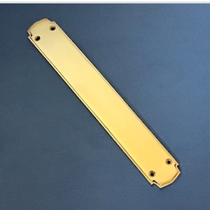 Puede incluir: Un tirador de puerta largo, rectangular, de latón con un borde decorativo festoneado. El tirador tiene dos agujeros para su montaje.